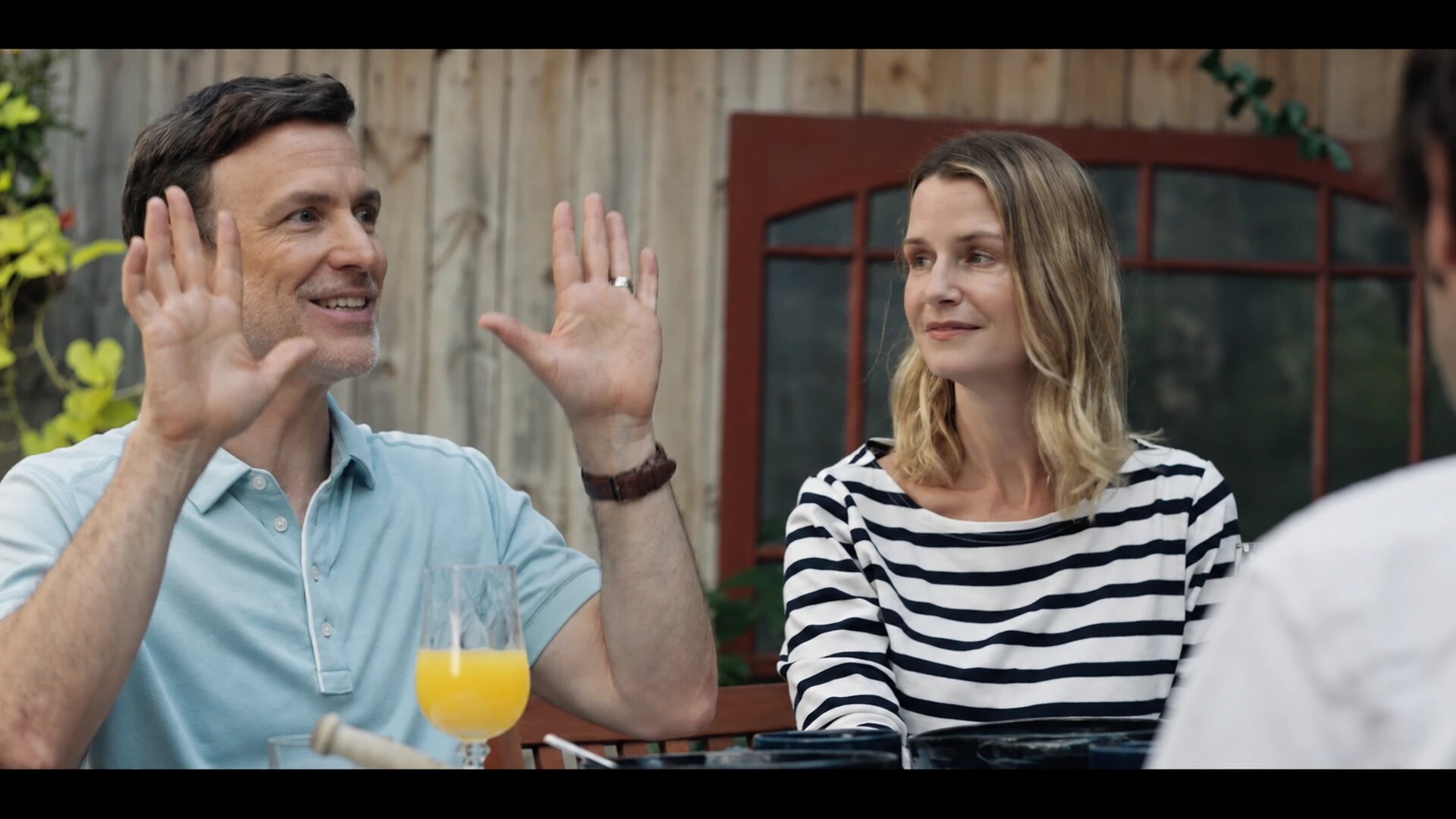 Mark gestures with both hands while Nancy looks on